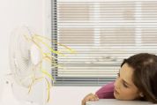 Junge Frau hält ihr Gesicht in einen Ventilator-Luftstrom Junge Frau hält ihr Gesicht in einen Ventilator-Luftstrom